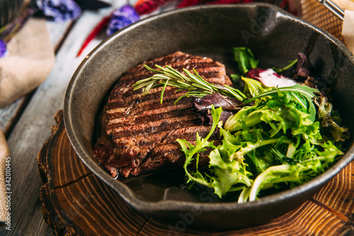 Appetizing juicy beef steak with greens in a pan