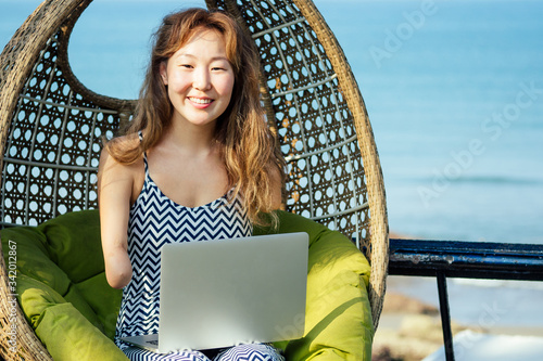 Fotografie happy asian freelancer businesswoman using a laptop in summer vacation on beach tropical resort