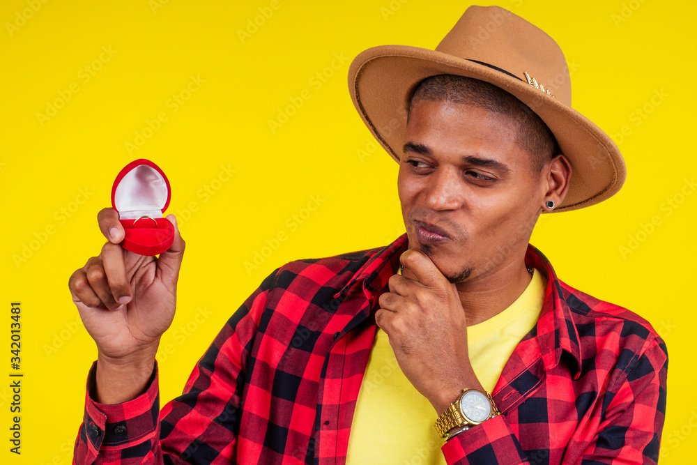 mexizan brazilian man showing box with ring in yellow wall mexizan brazilian man showing box with ring in yellow wall