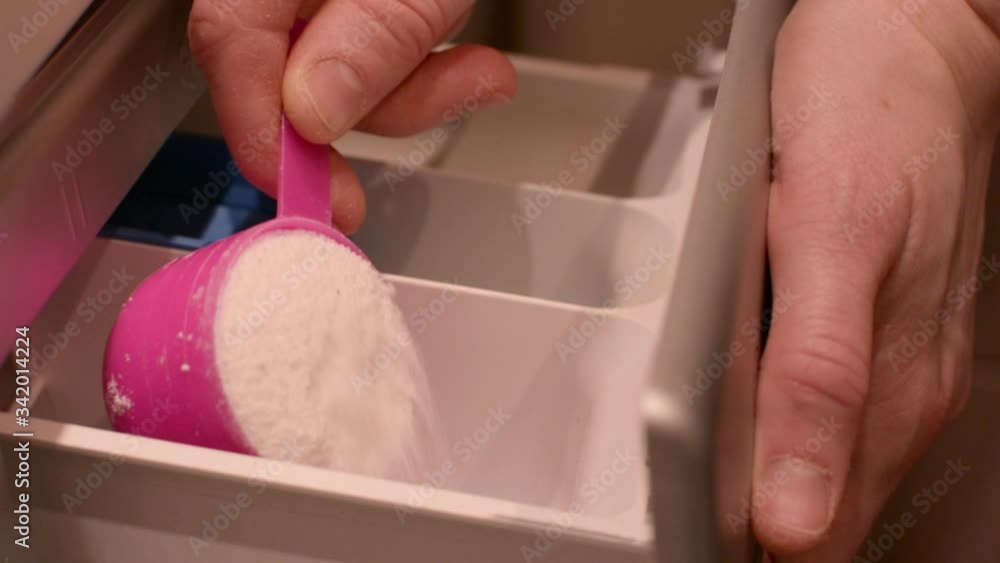 Woman adding detergent to compartment in washing machine and closing