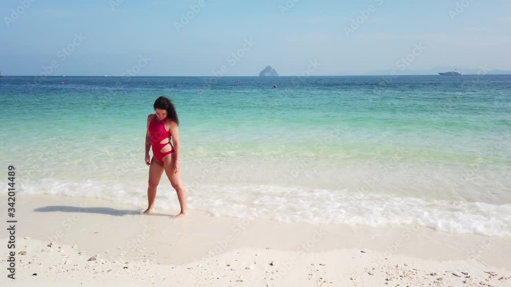 Girl brunette walks on the beach of an uninhabited island with azure water Girl brunette walks on the beach of an uninhabited island with azure water