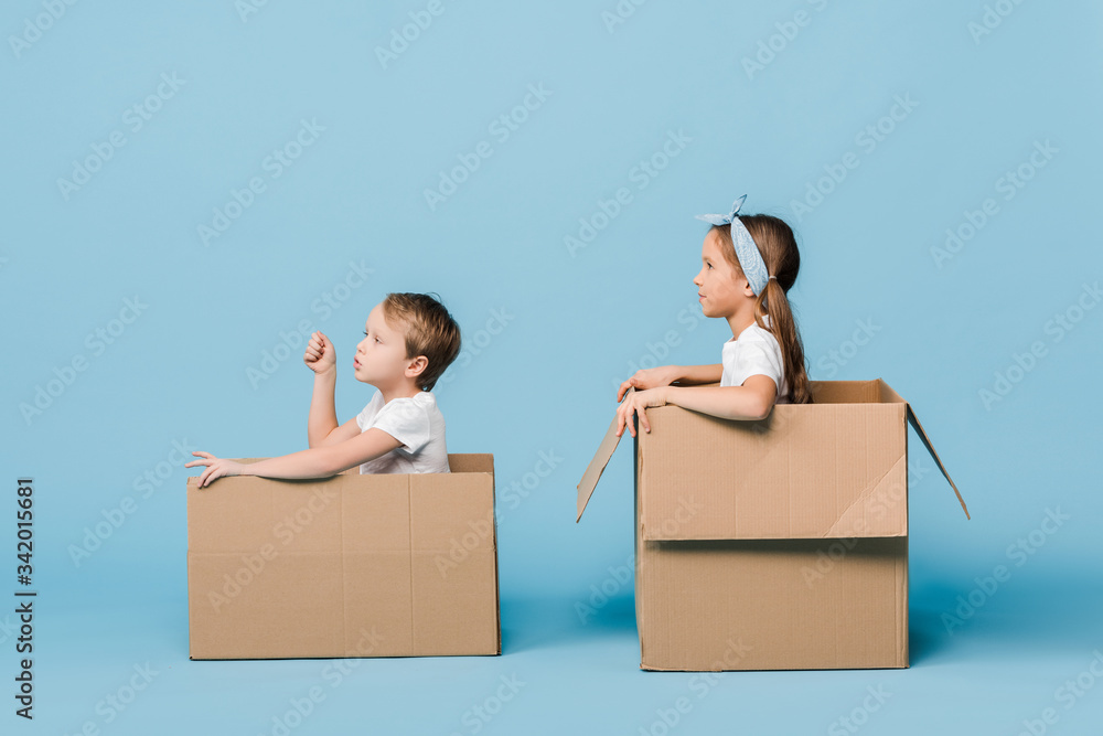 adorable siblings playing in cardboard boxes on blue adorable siblings playing in cardboard boxes on blue