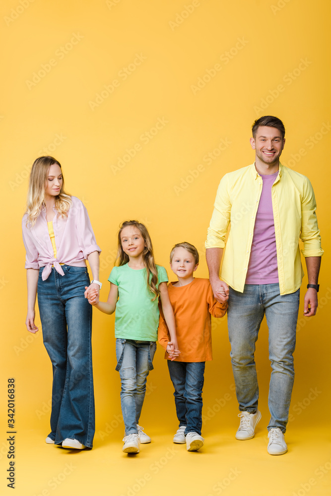happy parents holding hands with kids on yellow happy parents holding hands with kids on yellow
