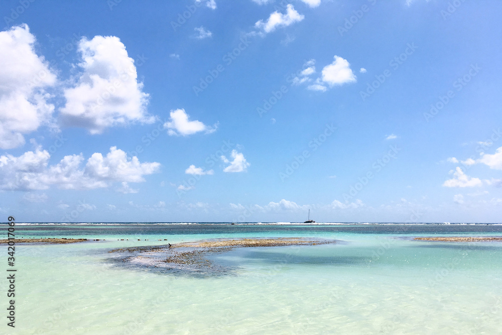 Ocean view with shallow light turquoise water and blue sky in Caribbean sea. Travel natural background. Tropical island view. Vacation recreation.