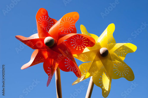 Children's bright toys in the sunlight against the blue sky. Turntables, weathercocks, whirligig, games with the wind. The concept of a sunny day and a happy childhood.