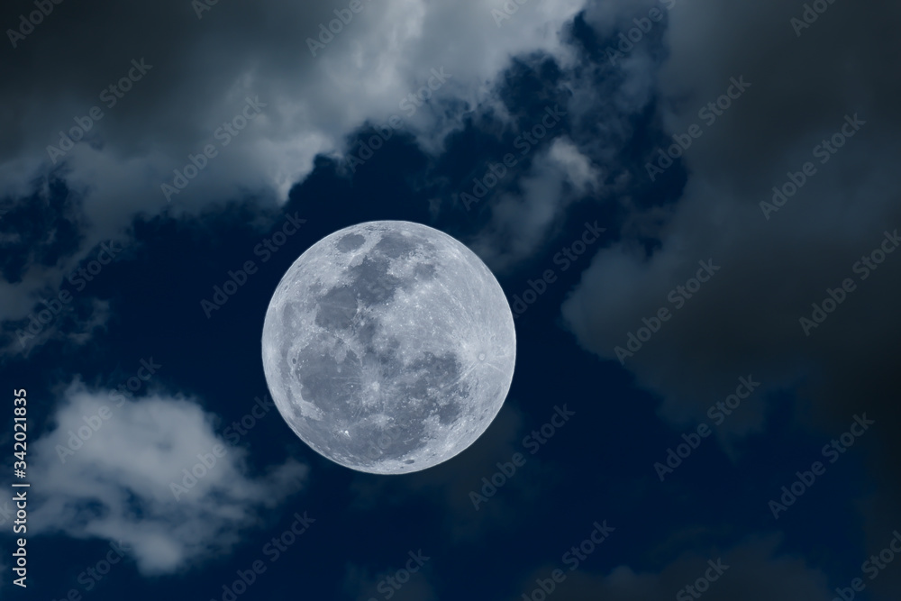 Full moon on the sky with blurred clouds.