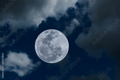 Full moon on the sky with blurred clouds.