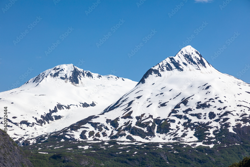 Snow capped rugged rocky mountains on blue sky day on the Kenai Peninsula of Alaska