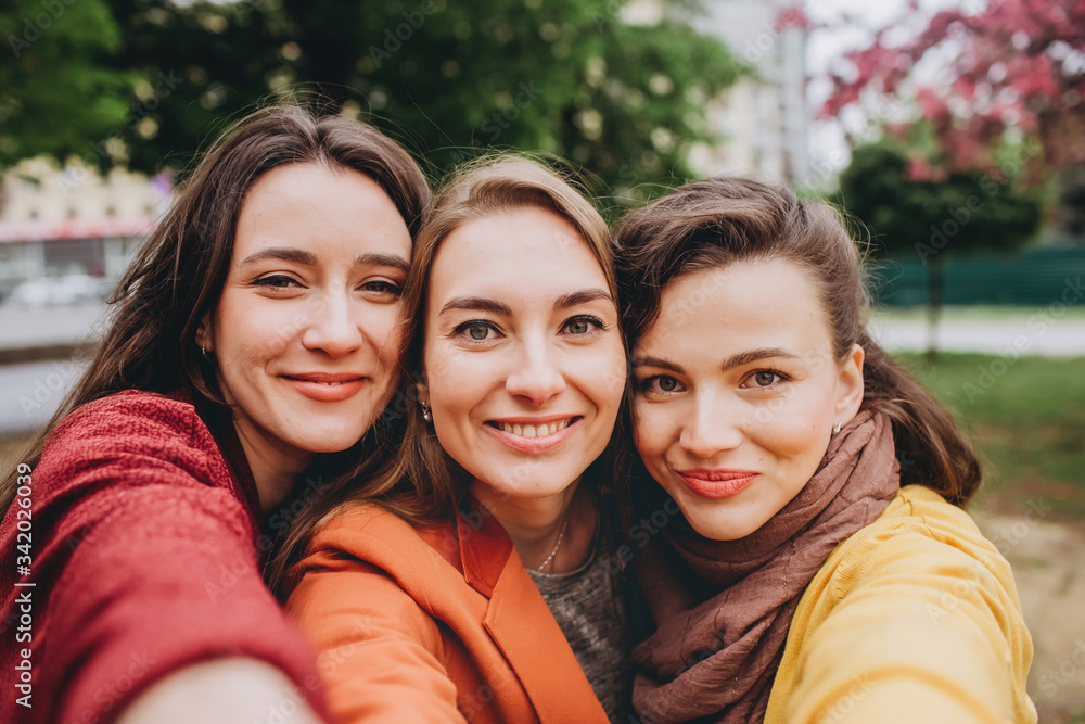 Obraz premium Best friends girls having fun, joy. Lifestyle. Beautiful young women in sunglasses dressed in the nice clothes smiling on a sunny day. photos of girls against the background of flowering trees