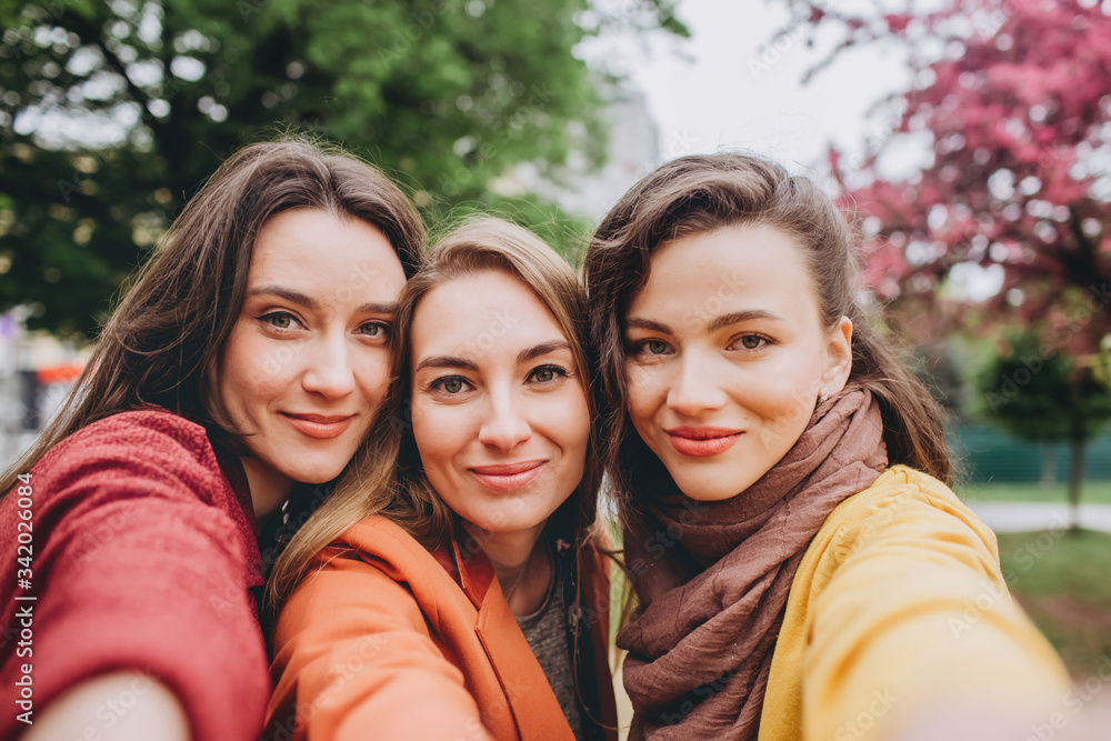 Obraz premium Best friends girls having fun, joy. Lifestyle. Beautiful young women in sunglasses dressed in the nice clothes smiling on a sunny day. photos of girls against the background of flowering trees