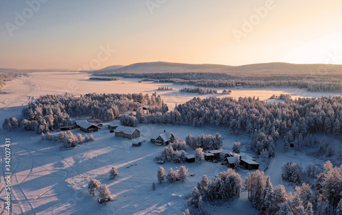 Aerial photo of frozen trees with lake in Lapland during winter.
