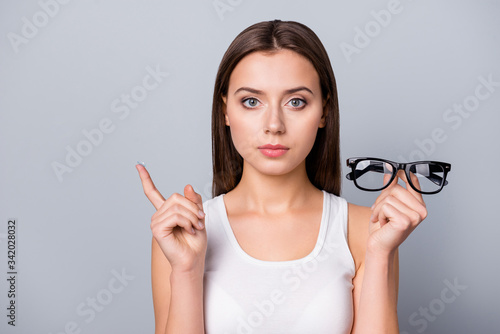 Close-up portrait of her she nice attractive lovely cute content calm brown-haired girl holding in hands choosing specs lens prescription isolated over grey pastel color background