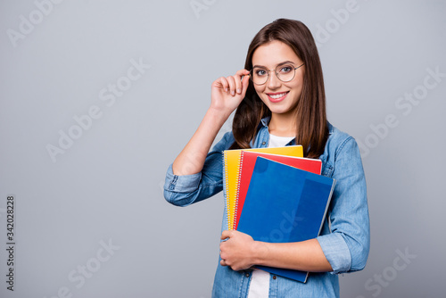 Close-up portrait of her she nice attractive lovely charming intelligent cheerful cheery girl holding in hands lesson exam test book materials isolated over grey pastel color background