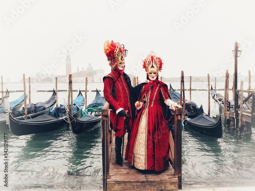 coppia in maschera per il carnevale di venezia di fronte alle gondole della laguna photo