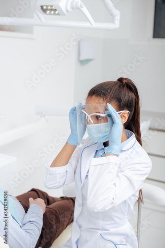 african american dentist in medical mask touching face shield near patient