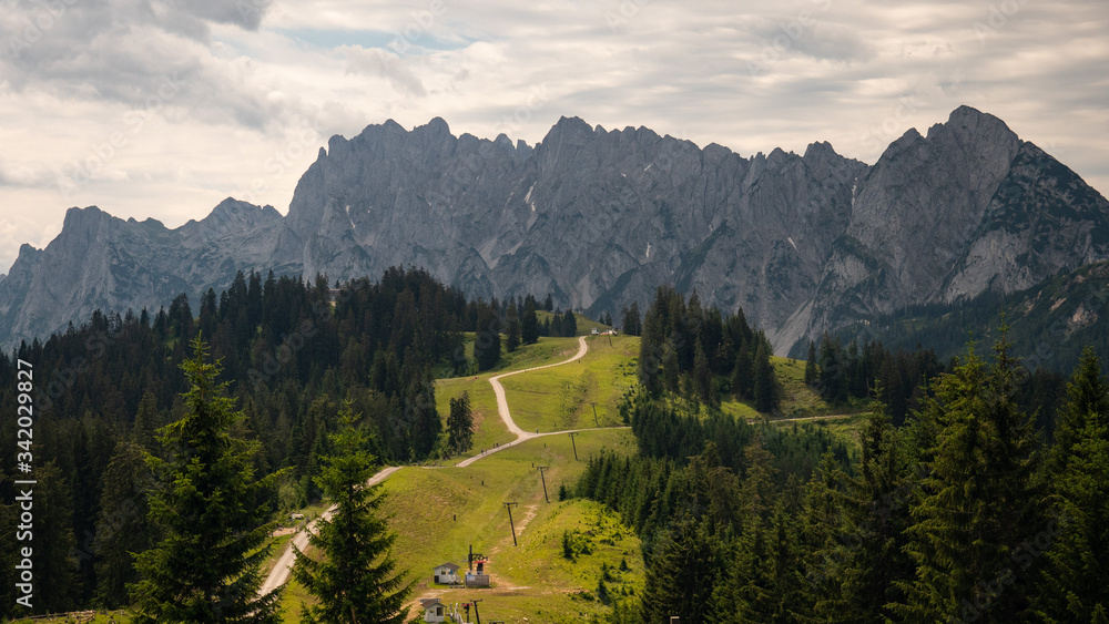 Aerial shot of ski slope in the salzburger land in the summer with huge mountains alps in background Aerial shot of ski slope in the salzburger land in the summer with huge mountains alps in background
