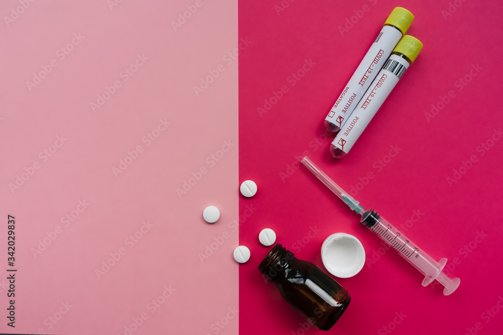Empty glass bottle with pills, two positive coronavirus tests and syringes. pink and red minimalist background concept Empty glass bottle with pills, two positive coronavirus tests and syringes. pink and red minimalist background concept