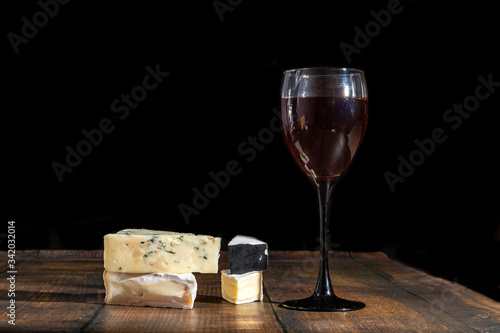 Delicious snacks and a glass of red wine. Different types of cheese on a dark background. Copy space for your text.