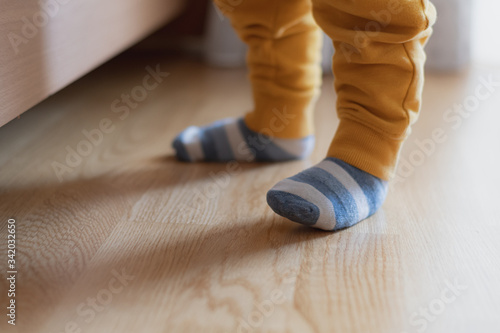 Obraz na płótnie Baby feet with striped socks, standing and trying his first steps, selective focus w salonie
