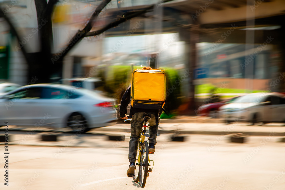 Courier on a bicycle to pick up and deliver an order from the fast food restaurant. Photo in motion. Coronavirus outbreak.