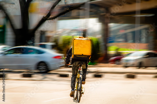Courier on a bicycle to pick up and deliver an order from the fast food restaurant. Photo in motion. Coronavirus outbreak. © Andrii Chagovets
