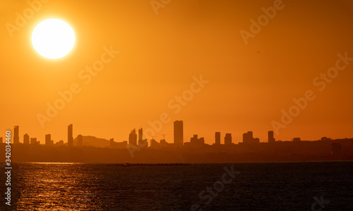 Huge sun and sunset over Benidorm city skyline and sea