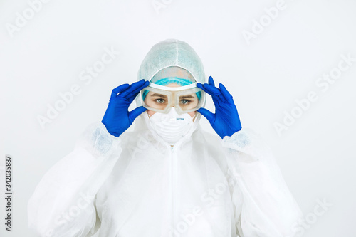 portrait of tired doctor after shift in the hospital. The doctor in protective clothing - glasses, mask, gloves on white background. The doctor treating patients with coronavirus. Covid-2019