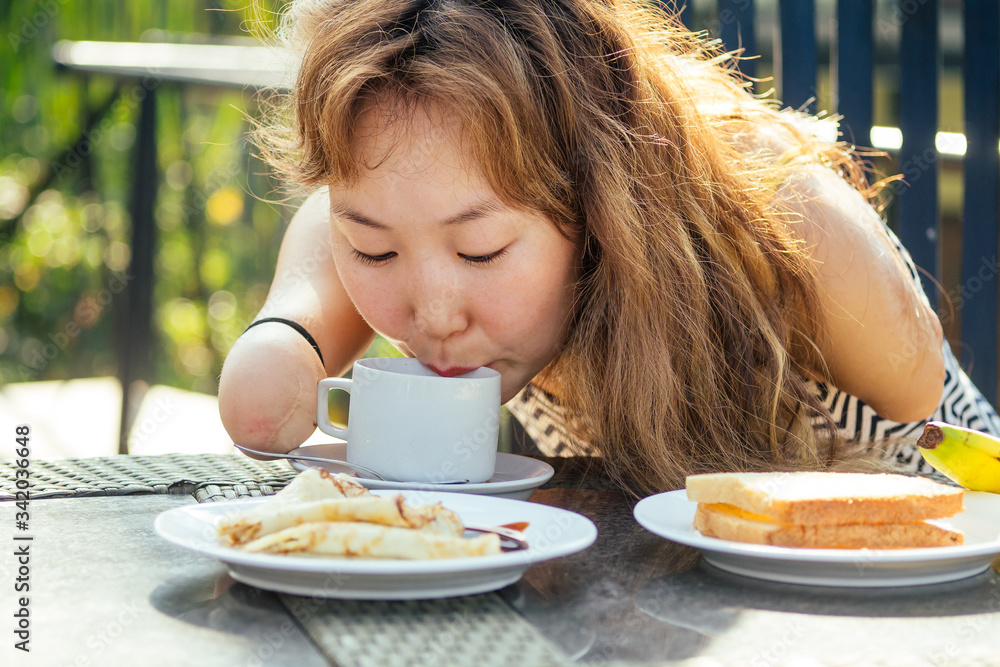beautiful asian woman eating breakfast at tropical resort.she is drinks cup of tea or coffee beautiful asian woman eating breakfast at tropical resort.she is drinks cup of tea or coffee