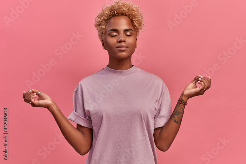 Photos Calm relieved blondish dark skinned woman takes deep breath, keeps hands sideway