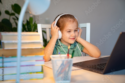 kid girl in headphones listens lesson on laptop