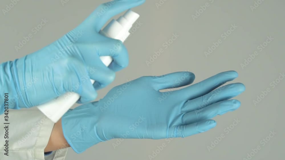 Splatters of spray antiseptic on blue medical gloves.On a white background.Compliance with sanitary rules and norms against viruses and diseases.Sprays disinfectant inside.Hands closeup.The nCoV virus Splatters of spray antiseptic on blue medical gloves.On a white background.Compliance with sanitary rules and norms against viruses and diseases.Sprays disinfectant inside.Hands closeup.The nCoV virus