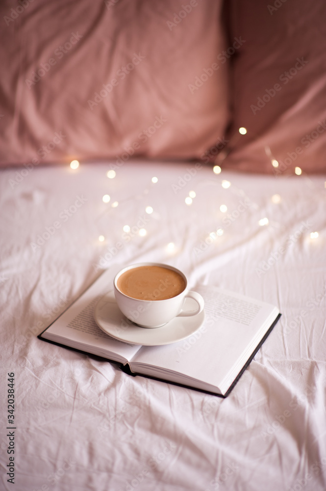 Cup of coffee with book in bed closeup. Good morning. Breakfast time.