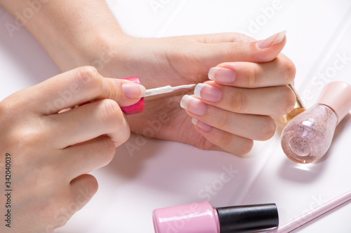 Manicure. A woman paints her nails. The girl applies nail Polish. French  nail care. Nail salon  procedure  SPA. Home nail care. Manicure tools. Beauty  nail art  Glamour