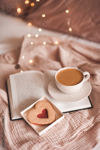 Cup of coffee with heart shape cake in bed closeup. Good morning. Breakfast. Valentines Day.