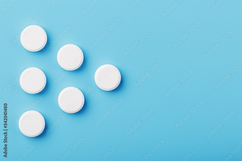Round medicinal tablets in the shape of a triangle on a blue background, isolate. Round medicinal tablets in the shape of a triangle on a blue background, isolate.