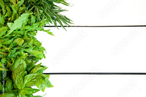 Assorted fresh green garden herbs on white wooden board, with copyspace for text or logo