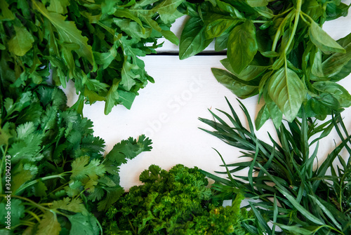 Mixed fresh green garden herbs on white wooden board, with copyspace for your text or logo
