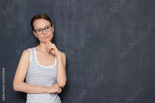 Portrait of focused girl with glasses, touching chin with hand