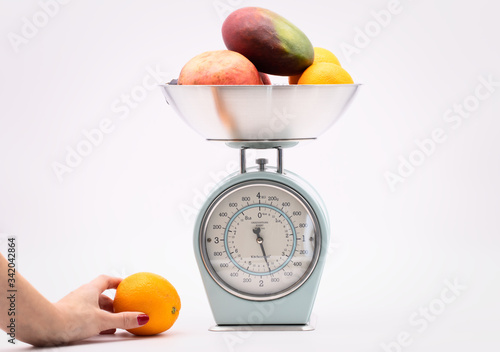 fruit on kitchen food scale on white background