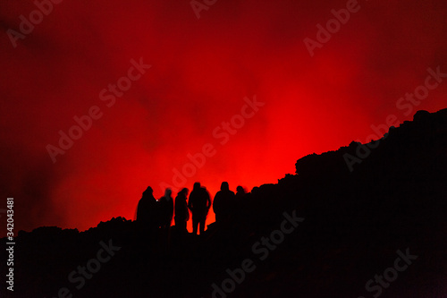 People watching lava glowing in volcano crater