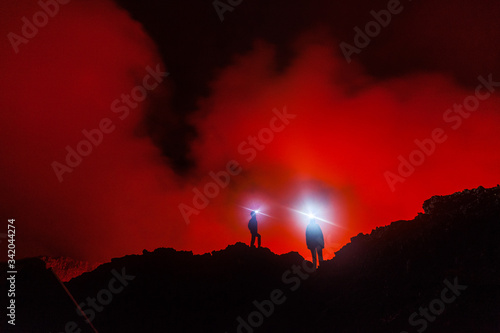 Tourists with the headlights are watching the lava moving inside the volcano