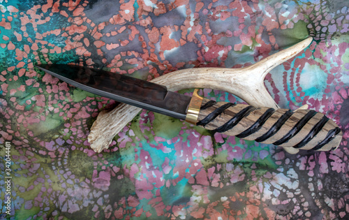 A one of a kind drop point bowie knife with hand forged damascus blade and myrtle wood handle with decorative grooves for a sure grip. Bokeh. photo