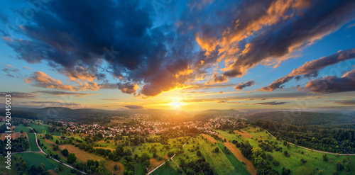 Aerial panorama of a vast landscape with a small town at a gorgeous colorful sunset with dramatic sky