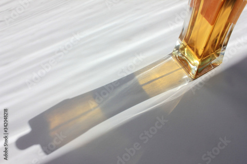 Photos Fragment of perfume spray bottle  in sunlight with long colored shadow on white background