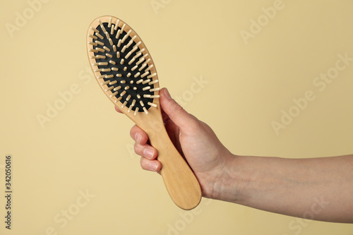 Εκτύπωση καμβά Female hand holds hair brush on beige background, close up