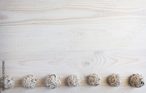 Energy balls using oatmeal and honey lie in a row on a light wooden background, copy space, top view