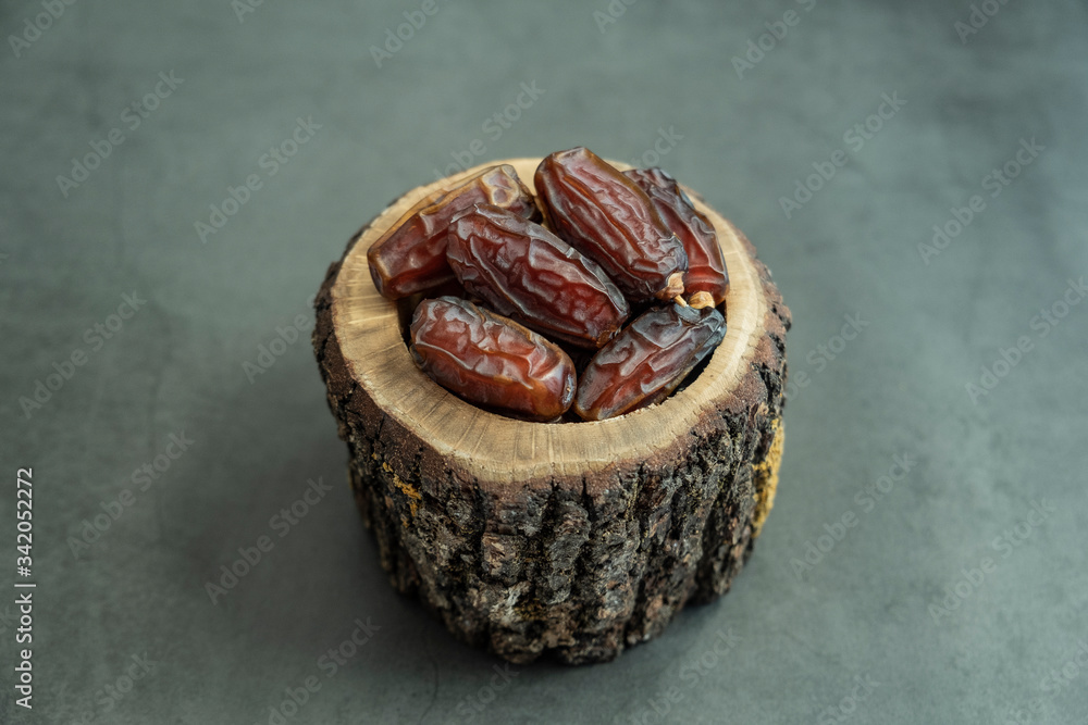 Raw date fruit ready to eat in wooden bowl on concrete background. Traditional, delicious and healthy ramadan food. Raw date fruit ready to eat in wooden bowl on concrete background. Traditional, delicious and healthy ramadan food.