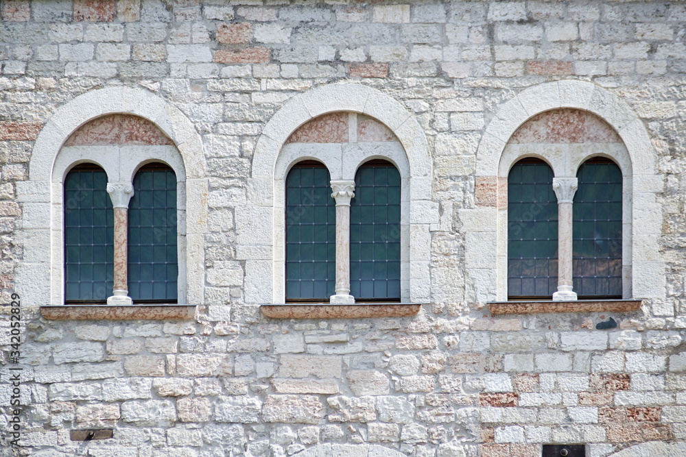 Three Italian antique windows on the old castle stone wall facade