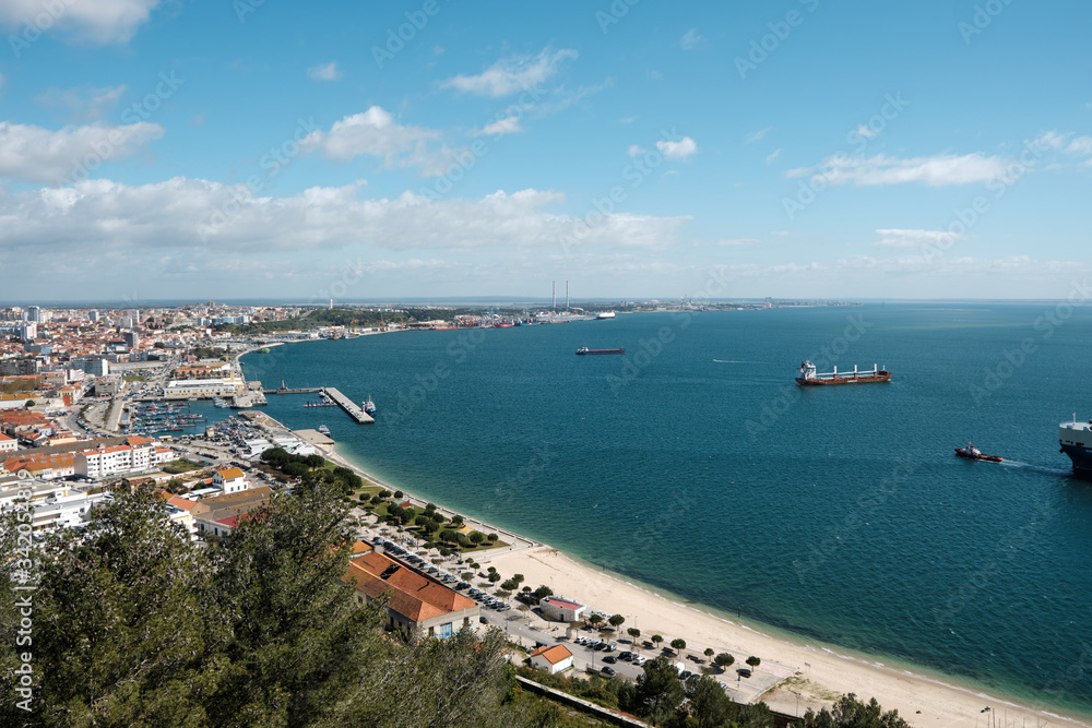 A sunny Portuguese bay with moored cargo ships and a busy harbour 