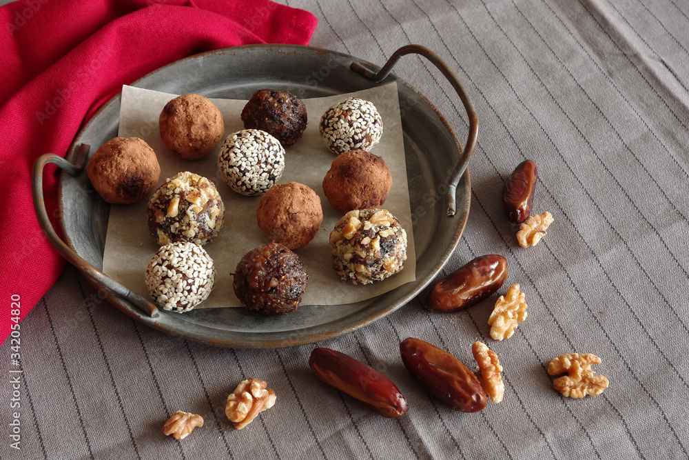 dried fruit sweets, for a healthy diet, homemade energy balls help the body fight viruses,candies are in a metal, caramic dish on gray, white textile background, horizontai frame dried fruit sweets, for a healthy diet, homemade energy balls help the body fight viruses,candies are in a metal, caramic dish on gray, white textile background, horizontai frame